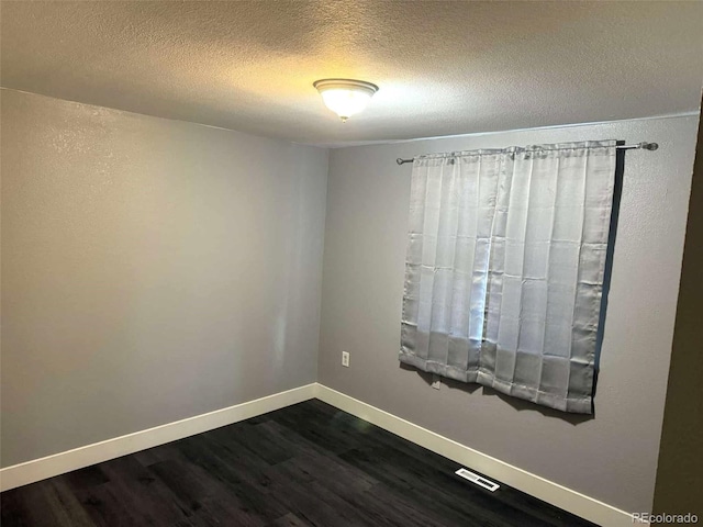 unfurnished room with a textured ceiling and dark wood-type flooring