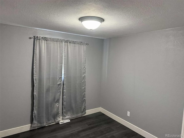 unfurnished room featuring dark hardwood / wood-style flooring and a textured ceiling