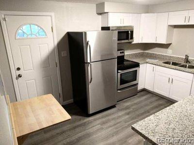 kitchen with light stone counters, white cabinetry, sink, and appliances with stainless steel finishes