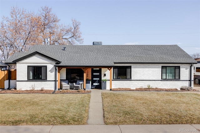 ranch-style house with brick siding, fence, a shingled roof, and a front yard