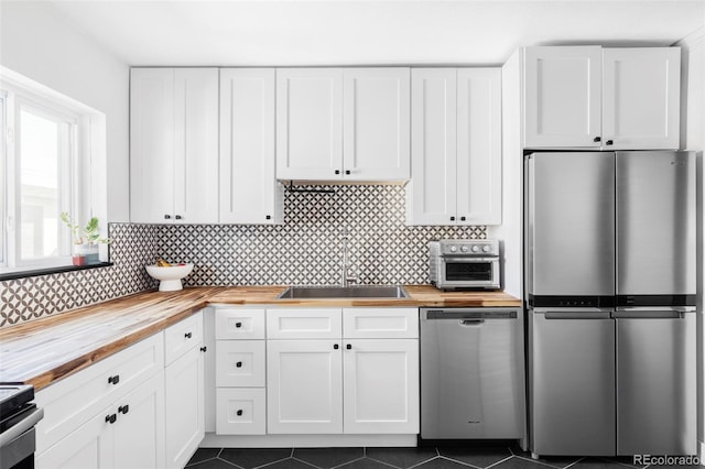 kitchen with white cabinets, appliances with stainless steel finishes, wooden counters, and a sink