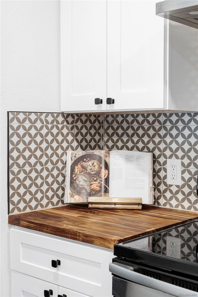 room details featuring decorative backsplash, wood counters, and white cabinets