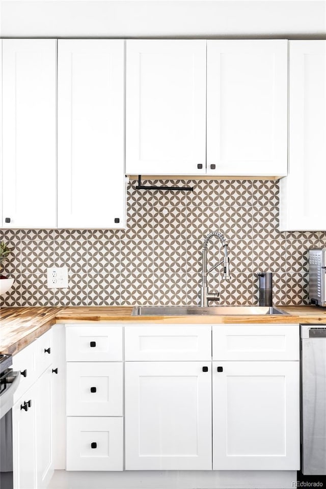 kitchen featuring white cabinets, a sink, butcher block counters, and dishwasher