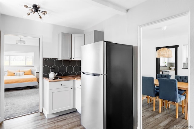 kitchen with freestanding refrigerator, backsplash, light wood finished floors, and butcher block countertops