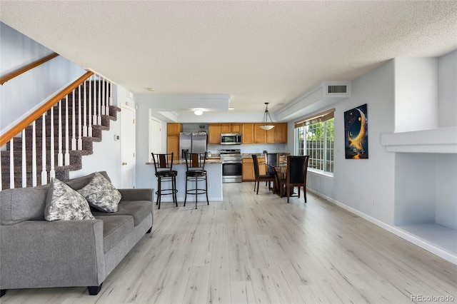 4184 Netherland St, Denver, CO 80249 - living room featuring light wood-style floors, stairs, a textured ceiling, and baseboards