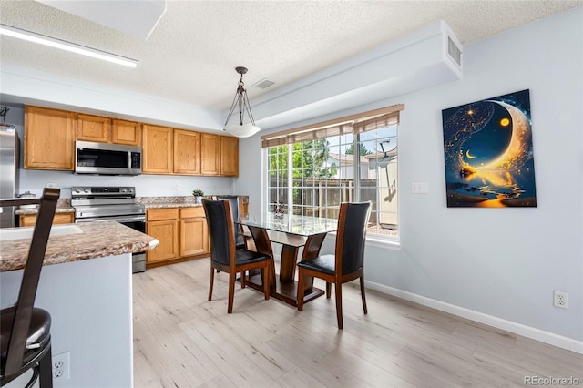 4184 Netherland St, Denver, CO 80249 - kitchen with stainless steel appliances, a textured ceiling, light wood-style flooring, hanging light fixtures, and baseboards