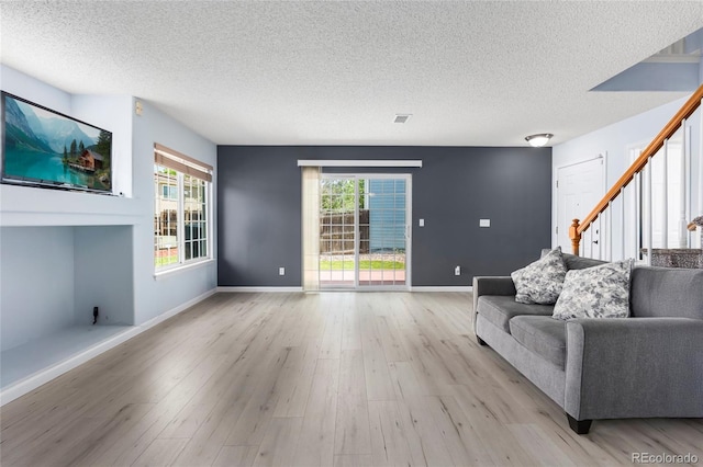 4184 Netherland St, Denver, CO 80249 - living room featuring a textured ceiling, light wood-type flooring, stairway, plenty of natural light, and baseboards