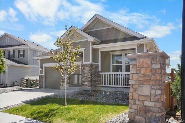 craftsman inspired home featuring driveway, stone siding, a porch, a garage, and a front yard