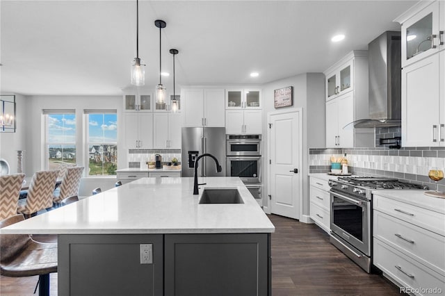 kitchen with premium appliances, a sink, wall chimney exhaust hood, light countertops, and backsplash