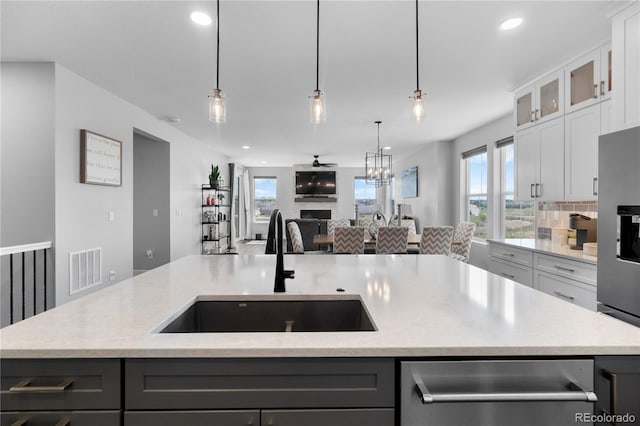 kitchen featuring a sink, open floor plan, a kitchen island with sink, recessed lighting, and light stone countertops