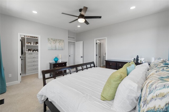 bedroom featuring a spacious closet, recessed lighting, light colored carpet, baseboards, and a ceiling fan