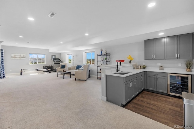 kitchen featuring wine cooler, gray cabinetry, a sink, a peninsula, and open floor plan