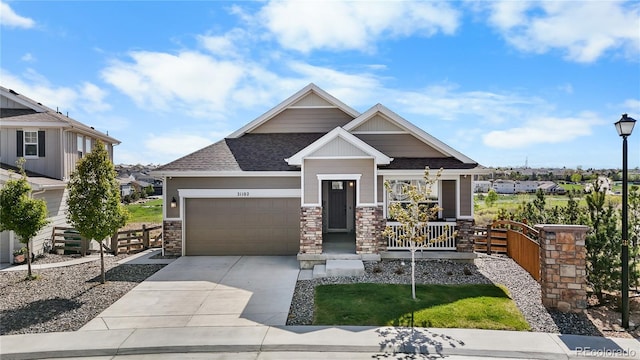 craftsman house with covered porch, a garage, driveway, and stone siding