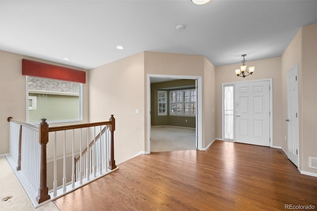 foyer with baseboards, an inviting chandelier, wood finished floors, and visible vents