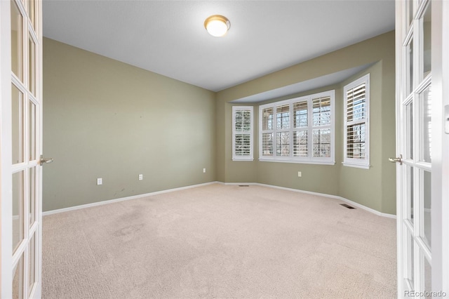spare room with baseboards, carpet flooring, visible vents, and french doors