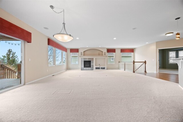 unfurnished living room with plenty of natural light, carpet flooring, baseboards, and a fireplace
