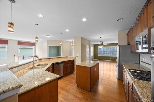 kitchen with a sink, light wood-style floors, stainless steel appliances, and a spacious island