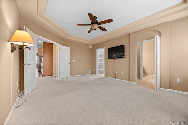 unfurnished bedroom featuring baseboards, light carpet, ceiling fan, and a raised ceiling