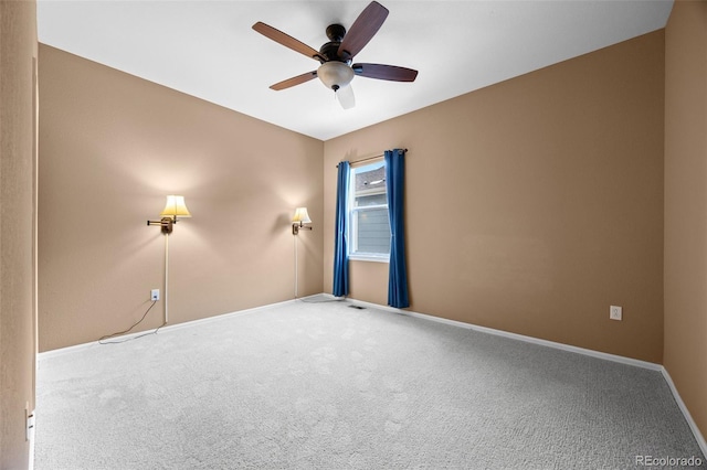 carpeted spare room featuring ceiling fan and baseboards