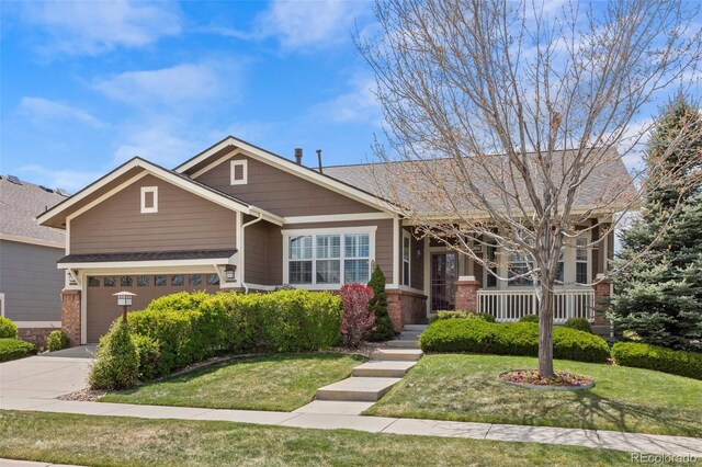 craftsman house featuring concrete driveway, brick siding, a front yard, and a garage