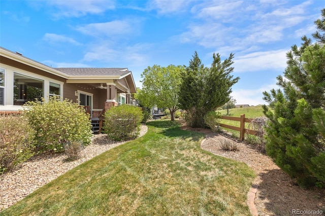 view of yard with fence and a ceiling fan