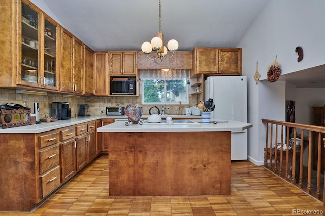 kitchen with vaulted ceiling, a kitchen island, decorative light fixtures, backsplash, and a chandelier