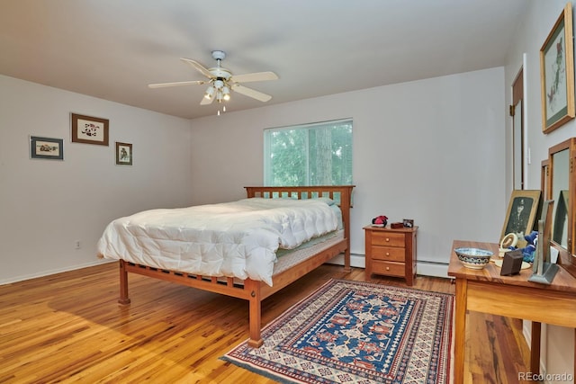 bedroom featuring ceiling fan, wood-type flooring, and a baseboard heating unit