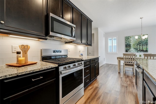 kitchen with light stone counters, appliances with stainless steel finishes, light wood-type flooring, decorative backsplash, and pendant lighting