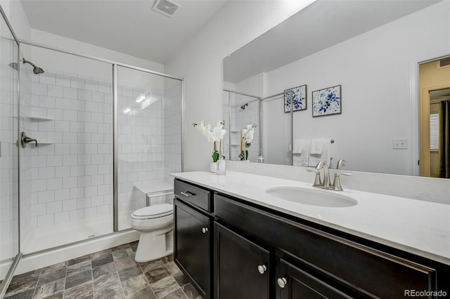 bathroom with toilet, vanity, visible vents, and a shower stall