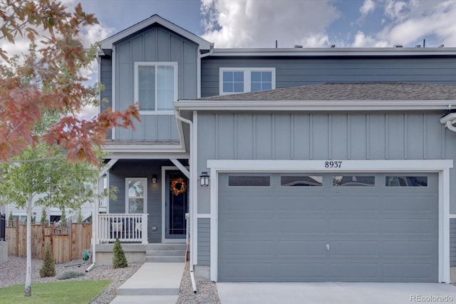 view of front of house featuring driveway, fence, board and batten siding, and roof with shingles