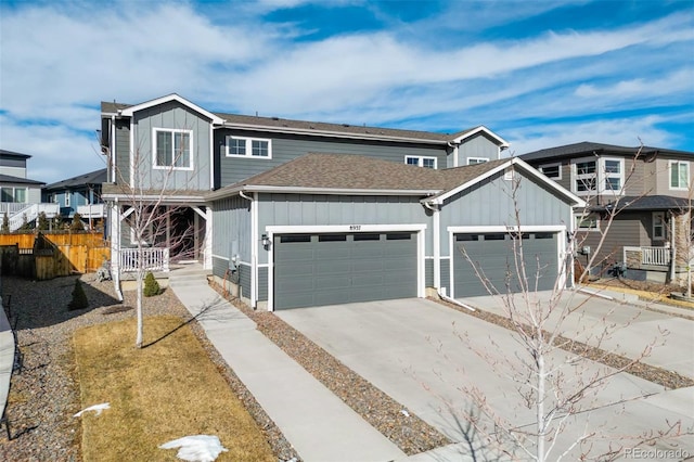 view of front of home with a garage, a shingled roof, concrete driveway, fence, and board and batten siding