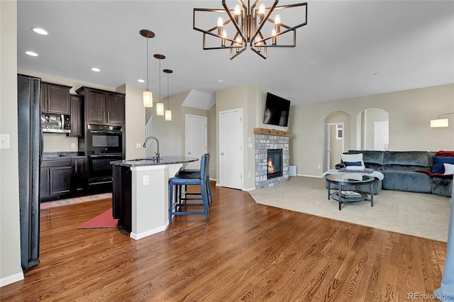 25486 E 4th Pl, Aurora, CO 80018 - kitchen featuring open floor plan, stainless steel microwave, a kitchen breakfast bar, wood finished floors, and recessed lighting