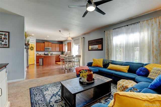 living area featuring a ceiling fan, light colored carpet, baseboards, and recessed lighting