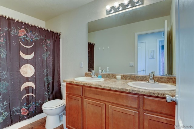 bathroom with double vanity, toilet, wood finished floors, and curtained shower