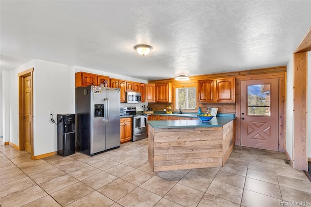 kitchen featuring kitchen peninsula, sink, light tile patterned flooring, and stainless steel appliances