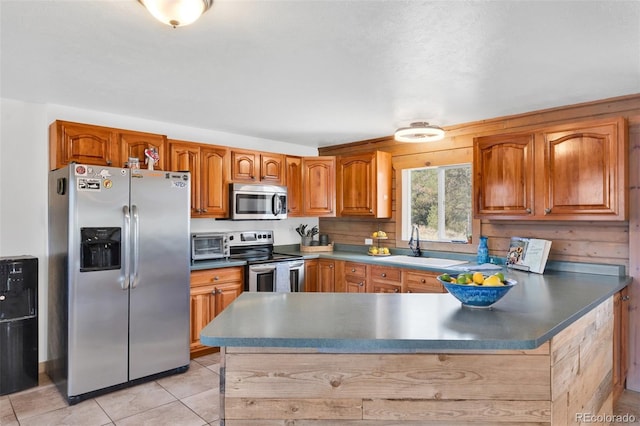 kitchen with kitchen peninsula, sink, light tile patterned floors, and stainless steel appliances