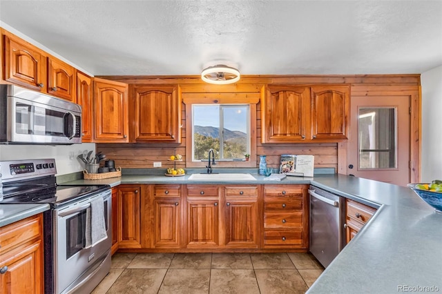 kitchen featuring a textured ceiling, light tile patterned floors, sink, and appliances with stainless steel finishes