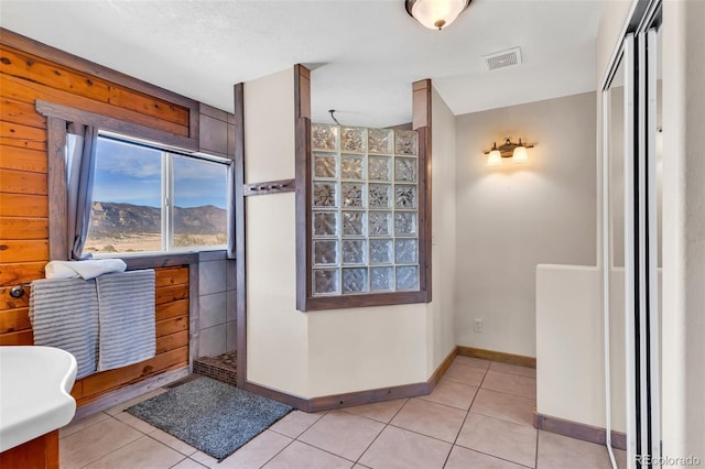 bathroom with tile patterned floors, a mountain view, wood walls, a textured ceiling, and vanity