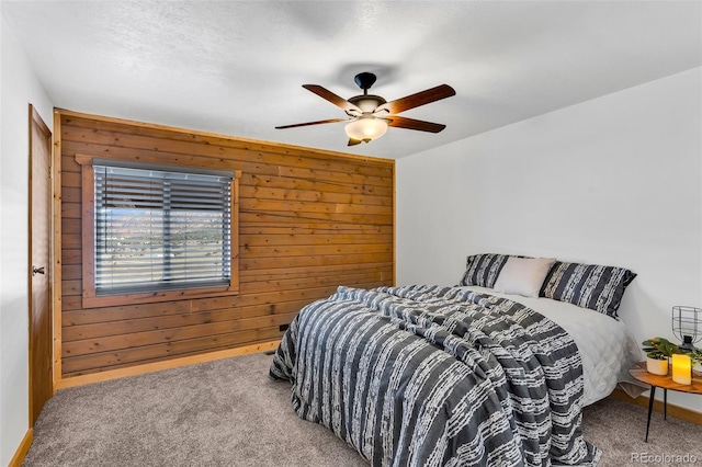 carpeted bedroom with ceiling fan and wood walls