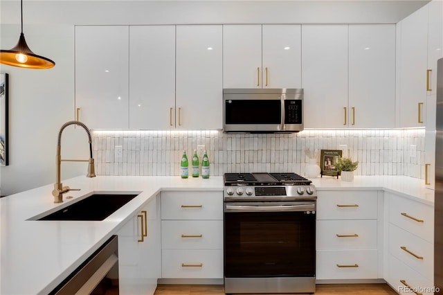 kitchen with stainless steel appliances, modern cabinets, a sink, white cabinetry, and light countertops