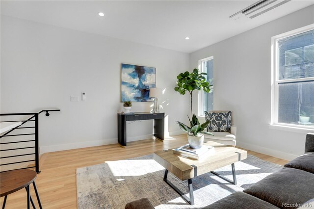 living room featuring light wood-type flooring, baseboards, and recessed lighting