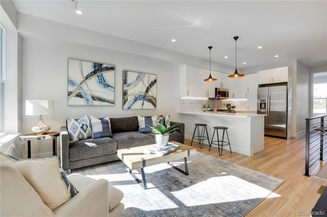 living area featuring light wood-style flooring, recessed lighting, and baseboards