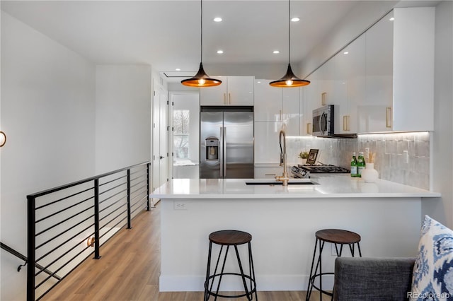 kitchen with stainless steel appliances, modern cabinets, a peninsula, a sink, and white cabinets
