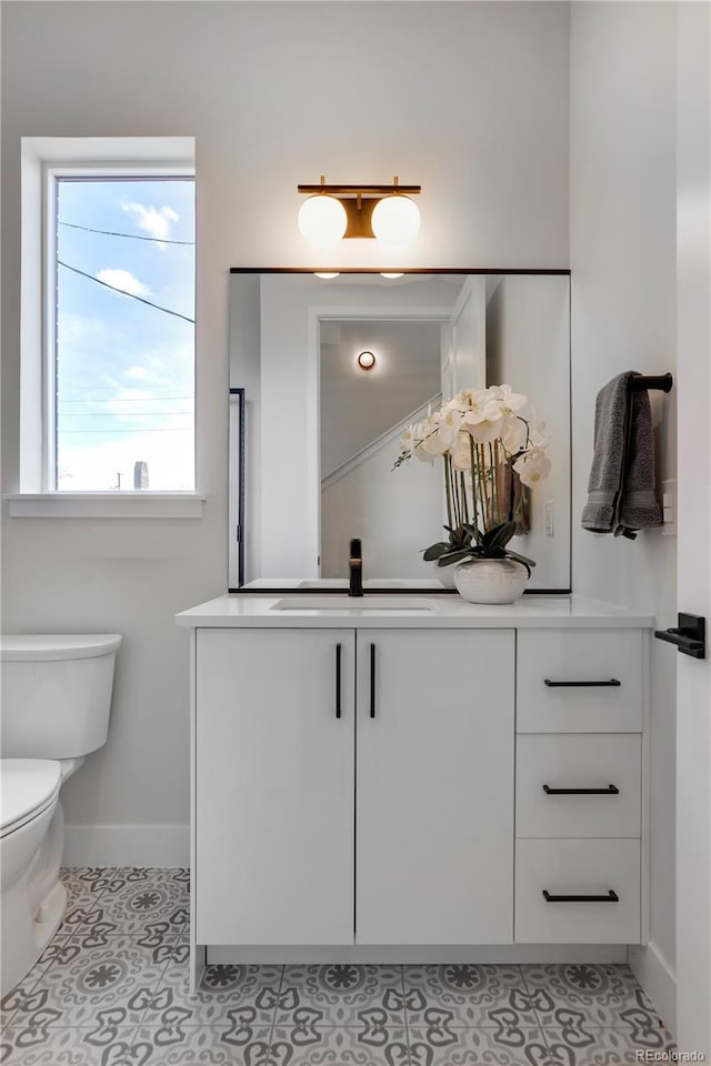 bathroom with baseboards, toilet, vanity, tile patterned flooring, and plenty of natural light