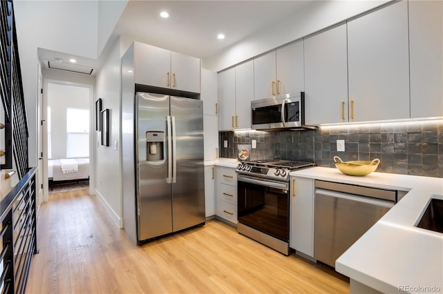 kitchen with appliances with stainless steel finishes, light wood-style floors, decorative backsplash, light countertops, and recessed lighting