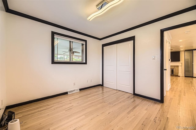 4244 W Monmouth Ave, Littleton, CO 80123 - unfurnished bedroom featuring crown molding, light wood finished floors, a closet, and a fireplace