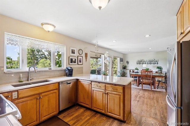1601 Columbine Pl, Colorado Springs, CO 80907 - kitchen featuring stainless steel appliances, wood finished floors, a peninsula, light countertops, and backsplash