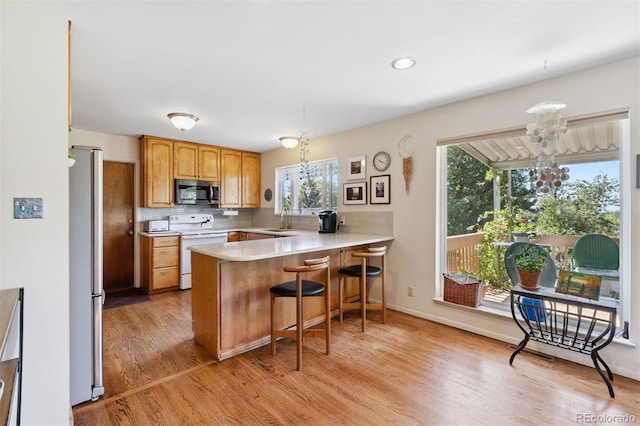 1601 Columbine Pl, Colorado Springs, CO 80907 - kitchen featuring appliances with stainless steel finishes, a peninsula, a chandelier, light wood-style flooring, and light countertops