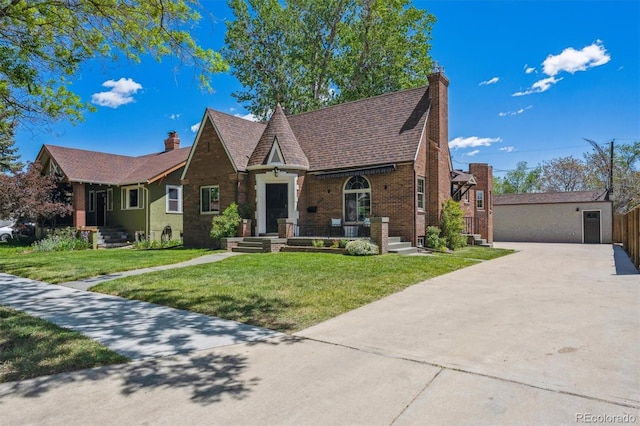 4434 Grove St, Denver, CO 80211 - tudor house featuring a chimney, brick siding, and a front yard