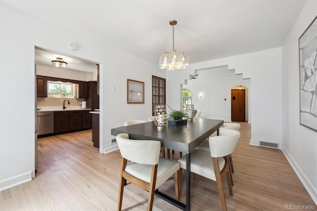 4434 Grove St, Denver, CO 80211 - dining space with light wood-style floors, a chandelier, and baseboards